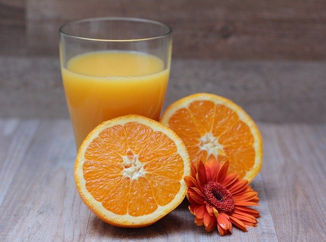 Pomarančová šťava v pohári a rozkrojený pomaranč